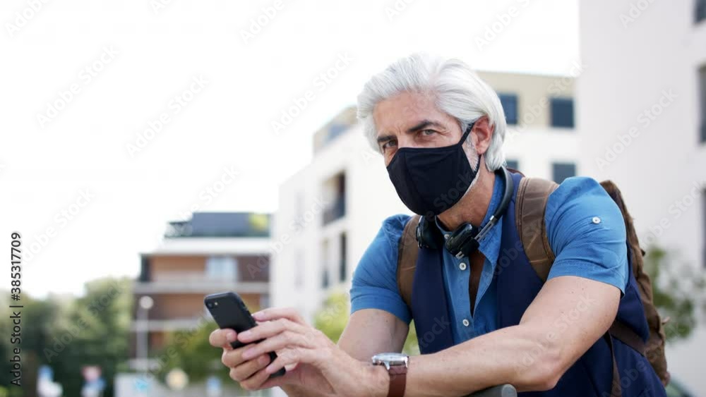 Mature man commuter with face mask and telephone outdoors in city, coronavirus concept. Mature man commuter with face mask and telephone outdoors in city, coronavirus concept.