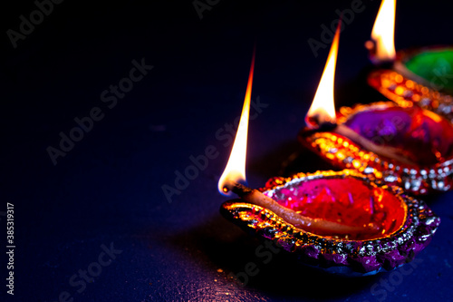 burning decorated ceramic oil lamp diya, on Happy Diwali, Shubh Diwali with beautiful dark blue background, copy space