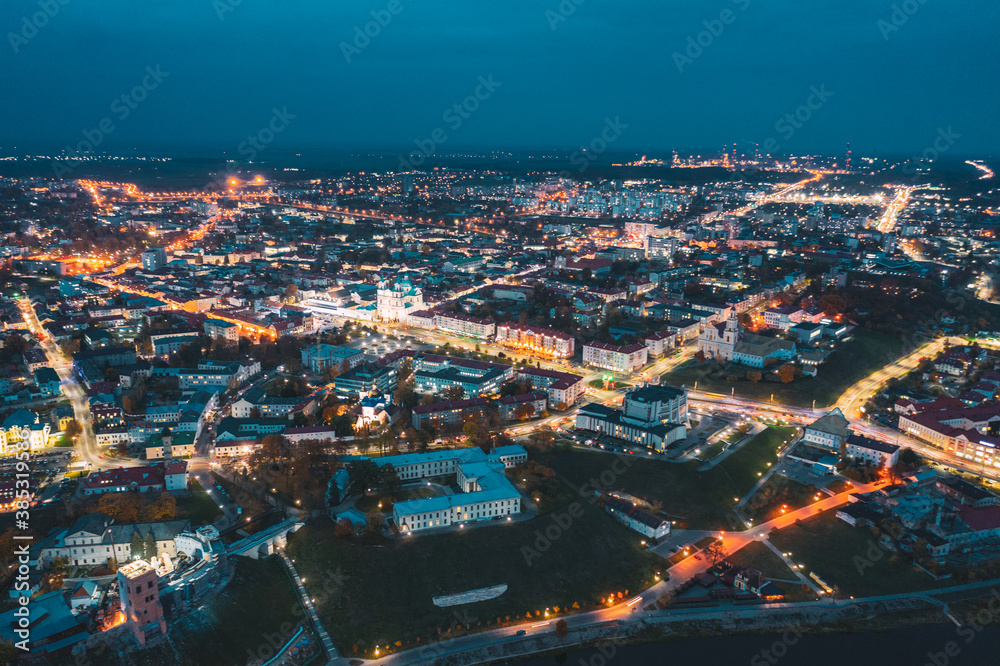 Grodno, Belarus. Night Aerial View Of Hrodna Cityscape Skyline. Famous Historic Landmarks In Lightning. Castles, Theater, Francis Xavier Cathedral, Catholic Church Of Discovery Of Holy Cross Grodno, Belarus. Night Aerial View Of Hrodna Cityscape Skyline. Famous Historic Landmarks In Lightning. Castles, Theater, Francis Xavier Cathedral, Catholic Church Of Discovery Of Holy Cross