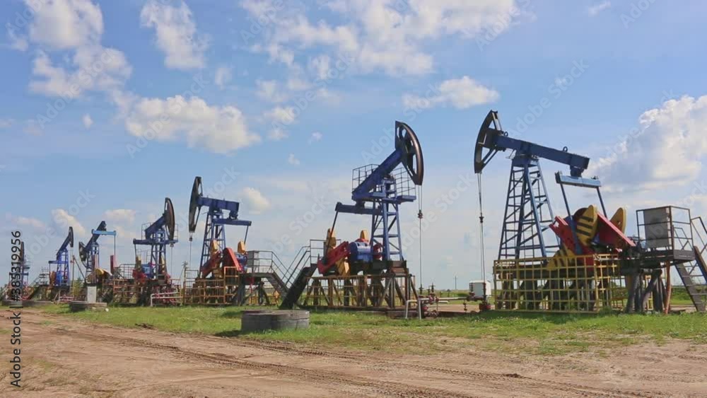Oil and gas industry. Working oil pump jack on a oil field with reflection on a puddle. White clouds and blue sky. Oil production. Oil and gas industry. Working oil pump jack on a oil field with reflection on a puddle. White clouds and blue sky. Oil production.