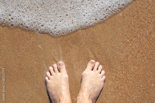 Woman bare feet on sand with sea foam