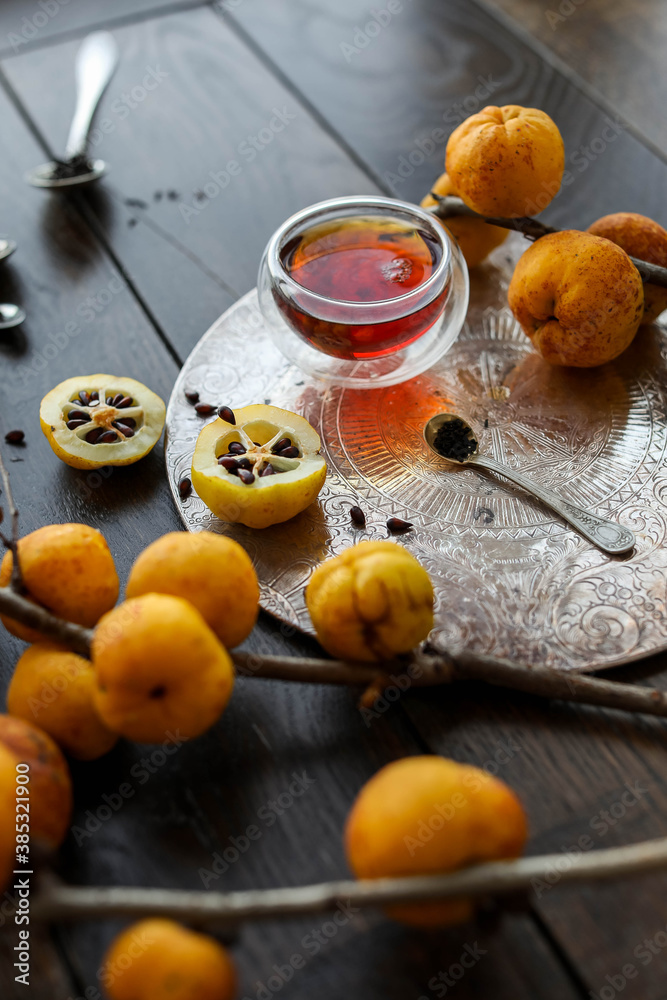 Autumn tea with quince. Small yellow quince fruits on the branches on a wooden table. Flat lay. Japanese. Autumn tea with quince. Small yellow quince fruits on the branches on a wooden table. Flat lay. Japanese.