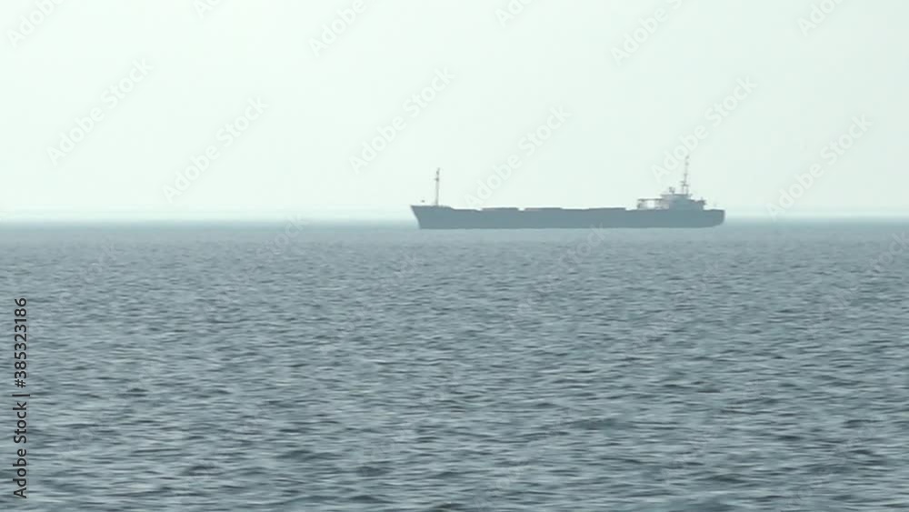 A cargo ship is sailing in a small mist on the sea horizon A cargo ship is sailing in a small mist on the sea horizon