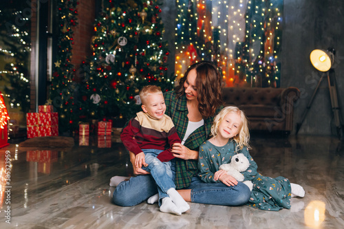 Cute mother with daughter and son posing at the Christmas tree © irina_timokhina