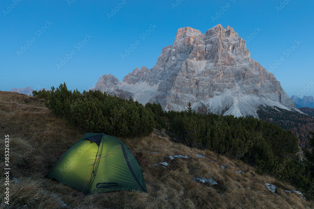 Green tent in landscape. Seasonal autumn scenery in the highlands. Alpine landscape in the Dolomites, South Tyrol, Italy. Popular destinations in autumn. Camping in nature concept.