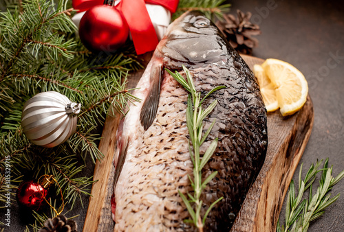 raw carp for preparation for the holiday Christmas on a background of stone with Christmas trees and Christmas decorations.
