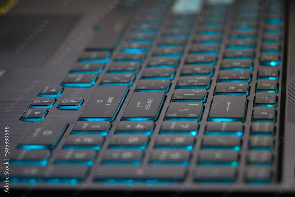 Closeup view of gaming laptop keyboard stroke with the blue backlit luminated on.