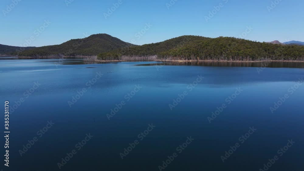 Blue Sky Reflecting At The Still Water Of Advancetown Lake - Forested Mountain From Hinze Dam - Gold Coast, Queensland, Australia. - aerial drone shot Blue Sky Reflecting At The Still Water Of Advancetown Lake - Forested Mountain From Hinze Dam - Gold Coast, Queensland, Australia. - aerial drone shot
