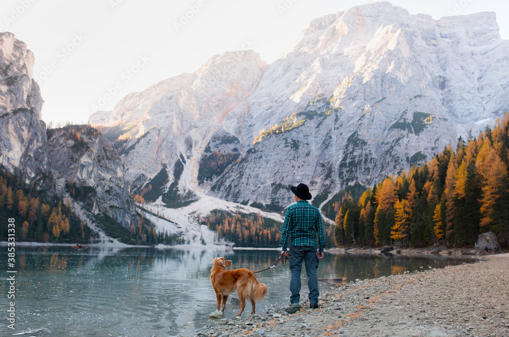 man with a dog at the famous mountain lake Braies in Italy. Traveling with a pet. High quality photo