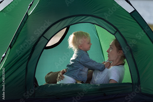 Mom and little child in tent in nature. Traveling with children, camping