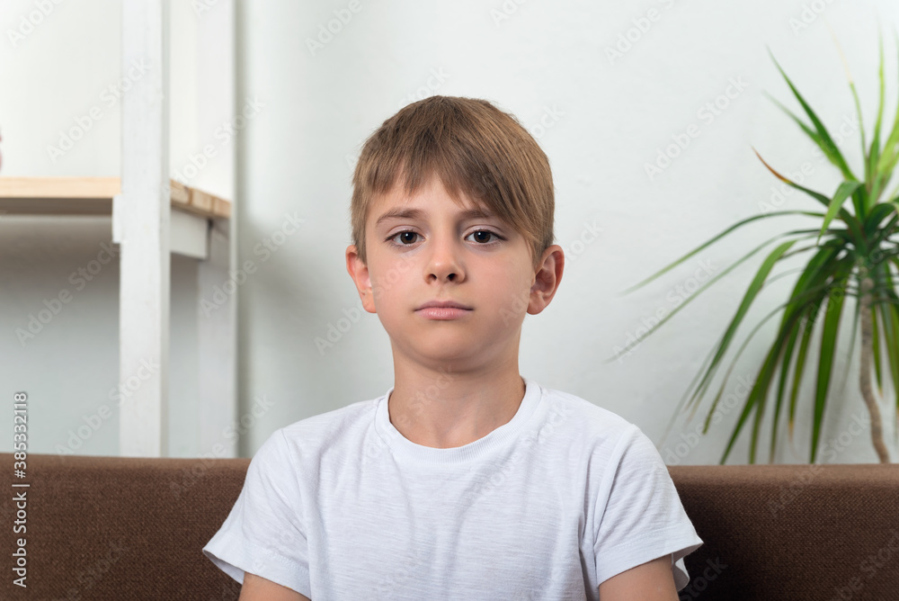 Portrait of teenage boy at home. Serious guy in white t-shirt Portrait of teenage boy at home. Serious guy in white t-shirt