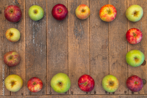 variety of apples layed out ina rectangular frame shape on a wood table