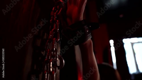 handcuffed woman during bdsm sex play, closeup of hand fixing by chain in dark room