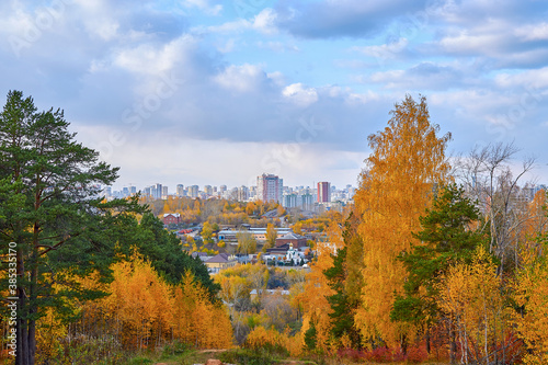 View of the colorful autumn forest and city, top view. View of the city from the mountain and yellowed trees
