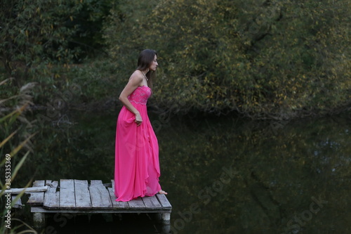 Beautiful woman in pink dress near the lake