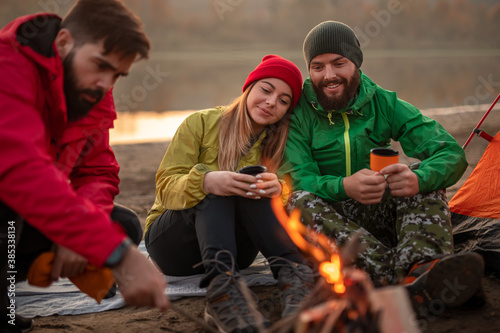 Couple resting near campfire with friend