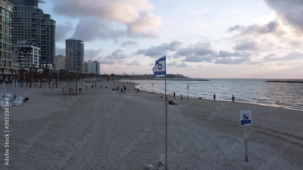 Spinning aerial shot around Israel waving flag at Tel-aviv beach at sunset, drone shot Spinning aerial shot around Israel waving flag at Tel-aviv beach at sunset, drone shot