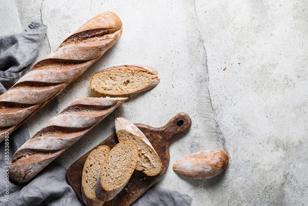 Fototapeta premium Top view of two brown baguettes on a concrete background.