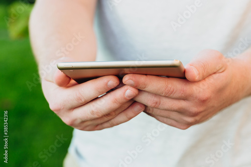 male hands holds digital pc t mock up for your text message or informational content, on the background of green nature