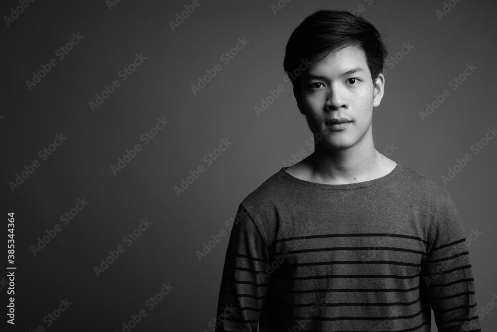 Young handsome Asian man against gray background Young handsome Asian man against gray background