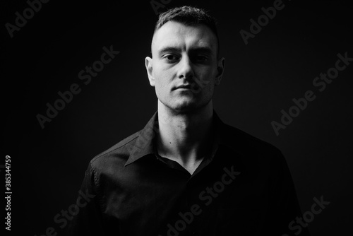 Portrait of young handsome businessman against gray background
