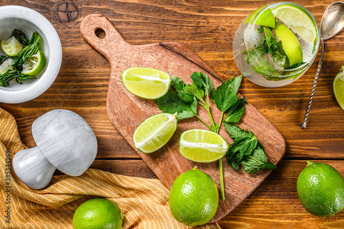 Fototapeta Naklejka Na Ścianę i Meble -  Drink making tools and ingredients for cocktail, lemonade, mojito. Lime, ice and mint. Wooden background. Top view