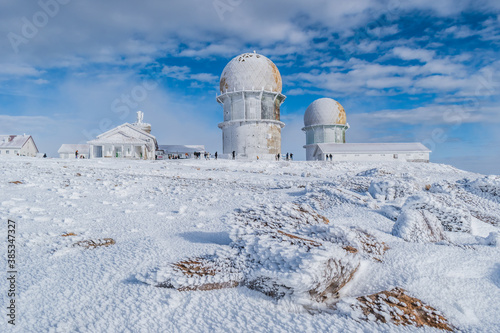 View to Serra da Estrela tower frozen, famous snow destination, with silhouettes of people in the background, Manteigas PORTUGAL