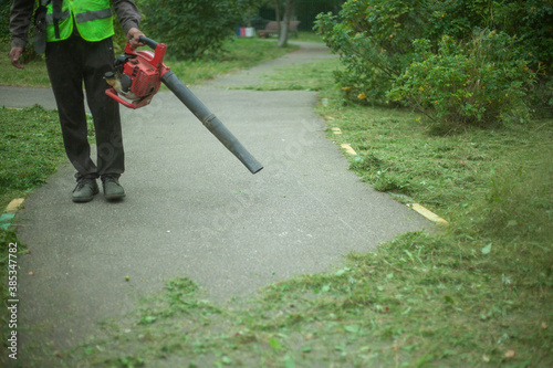 The gardener cleans up the park path. Leaf blower. 