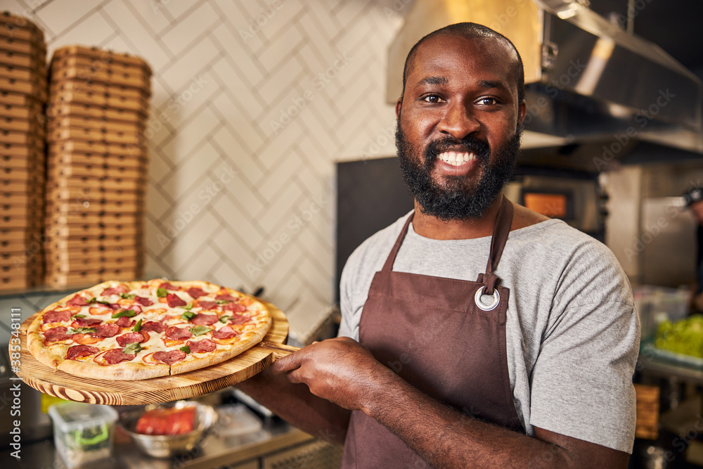Cheerful Afro American man holding pepperoni pizza