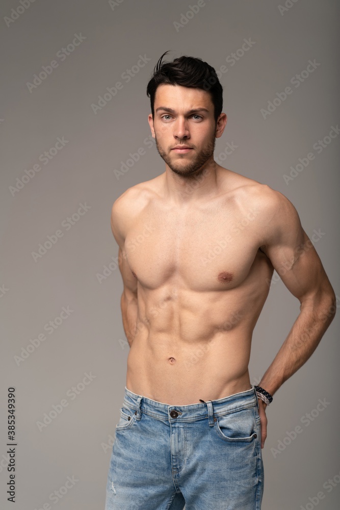 Portrait of a well built shirtless muscular male model against white background