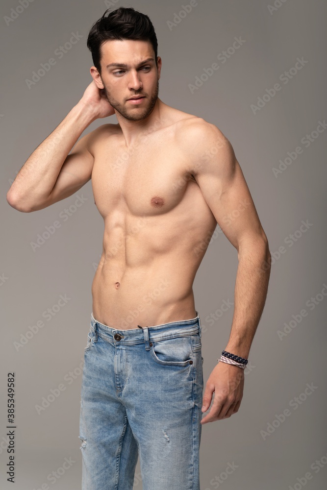 Portrait of a well built shirtless muscular male model against white background