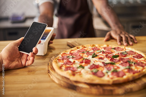 Male customer paying for pizza with smartphone