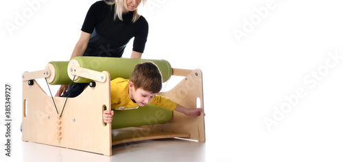 Boy and her mother showing principles of training on compact exercise equipment for children with special needs, isolated on white, copy space photo