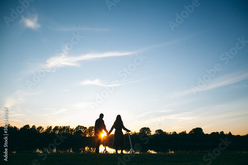 man and woman kissing at sunset  holding each other s hands  in nature  outdoors  hugs  tenderness