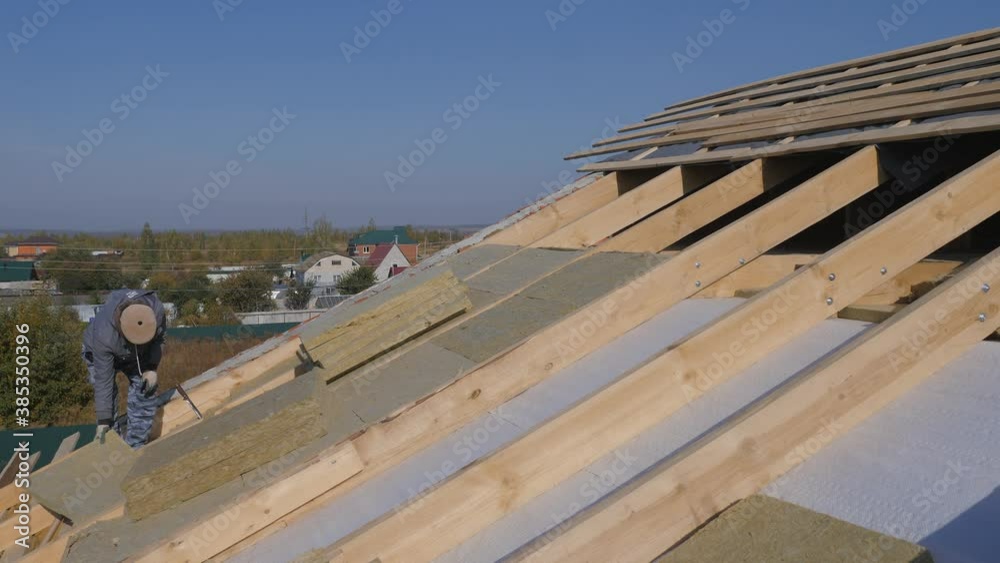 Construction work. Installation of insulation for insulation of the roof of a private house. Use of mineral wool. Laying of multi-layer thermal insulation material. Insulation of a private house with Construction work. Installation of insulation for insulation of the roof of a private house. Use of mineral wool. Laying of multi-layer thermal insulation material. Insulation of a private house with