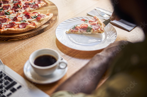 Afro American man placing slice of pizza on plate in cafe