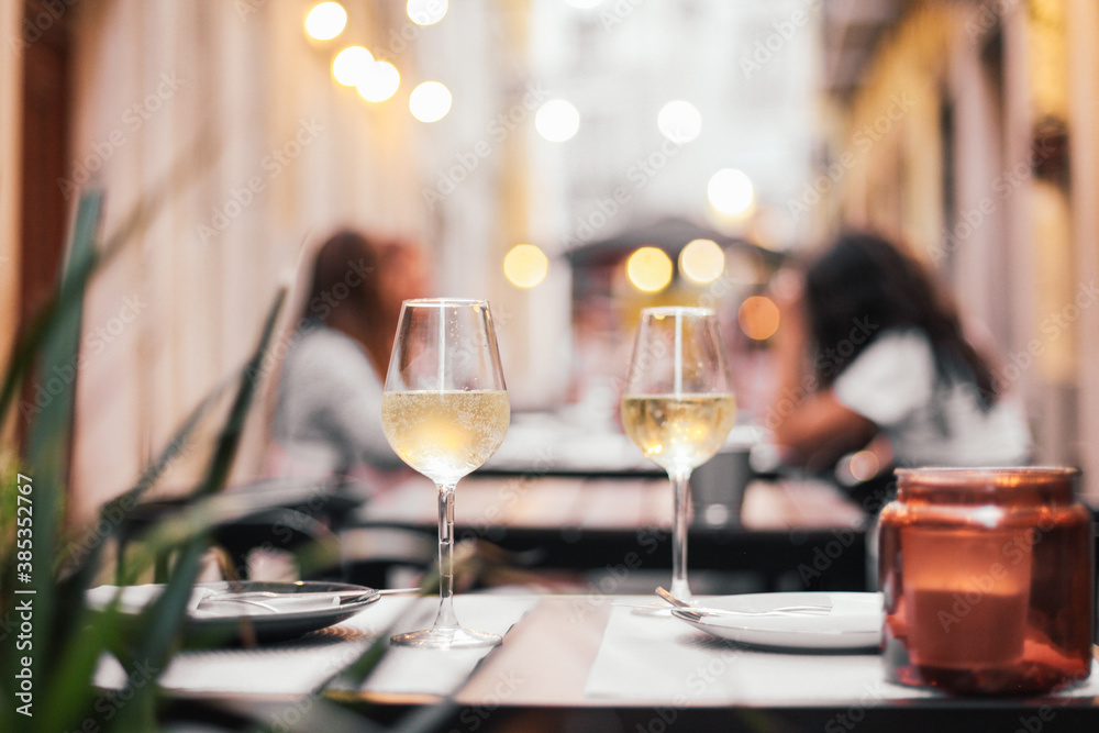 Two glasses of wine on a outdoor table, cozy evening, small street in Europe