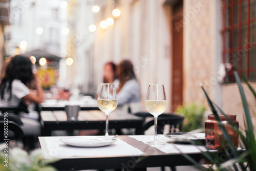 Two glasses of wine on a outdoor table, cozy evening, small street in Europe