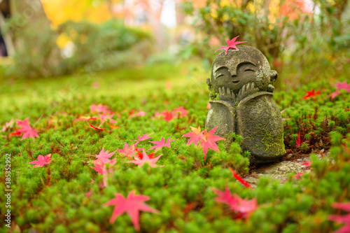 Canvas Print Red Maple leaf on head of Jizo sculpture doll (little Japanese Buddhist monk dol