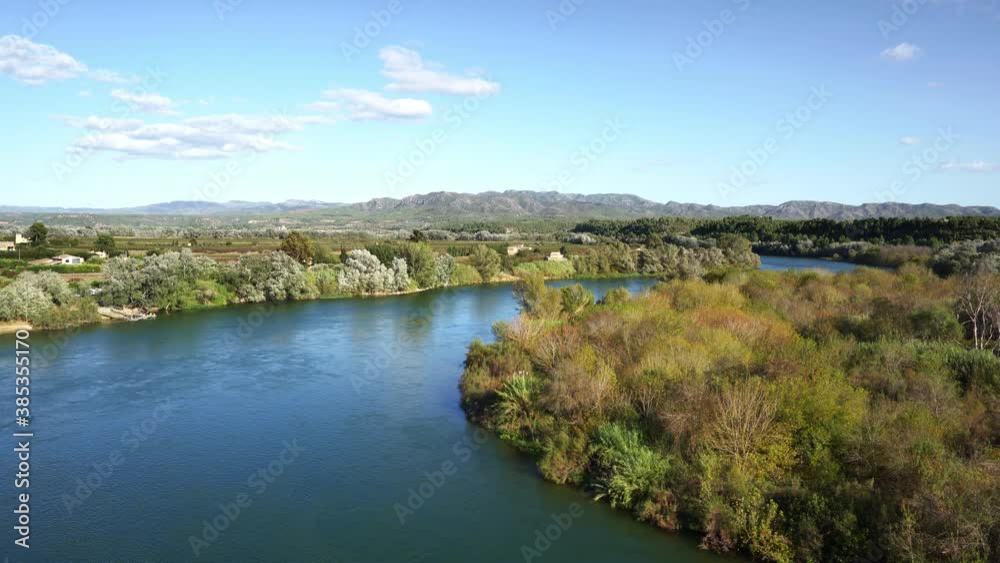 Ebro River passing through Miravet, Spain, with the Serra de Cardo and Els Ports mountain ranges in the background Ebro River passing through Miravet, Spain, with the Serra de Cardo and Els Ports mountain ranges in the background
