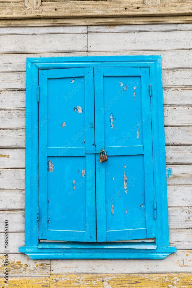 locked blue window on an old wooden house locked blue window on an old wooden house