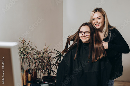 A female hairdresser of European appearance works with the hair of a model. Home beauty salon. Barbershop. Healthy strong hair.