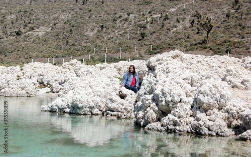 black hair latin woman in landscape of white rocks and water, turquoise blue lagoon. Alchichica Lagoon, Puebla Mexico photo