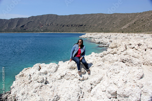 black hair latin woman in landscape of white rocks and water, turquoise blue lagoon. Alchichica Lagoon, Puebla Mexico photo