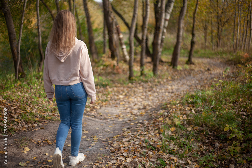 The girl walks along the path in the forest. Autumn walk in nature. The girl walks along the path in the forest. Autumn walk in nature.
