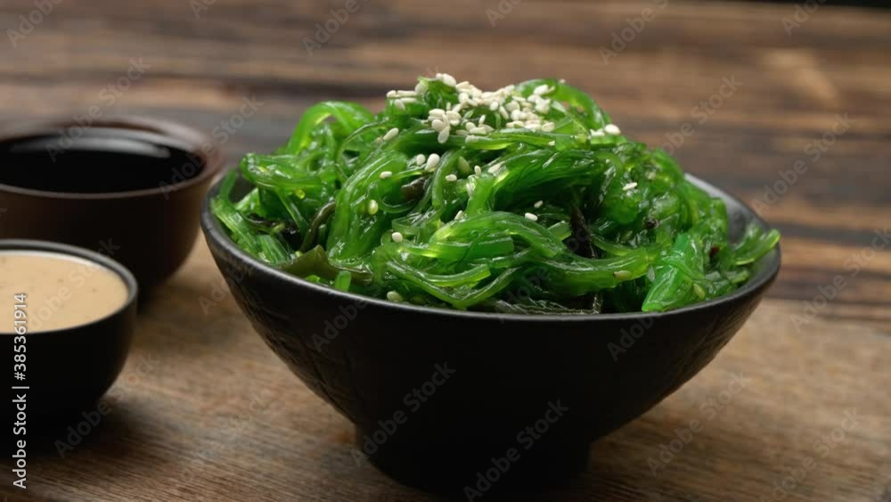 Bowl with tasty seaweed salad and sauces table, closeup Bowl with tasty seaweed salad and sauces table, closeup