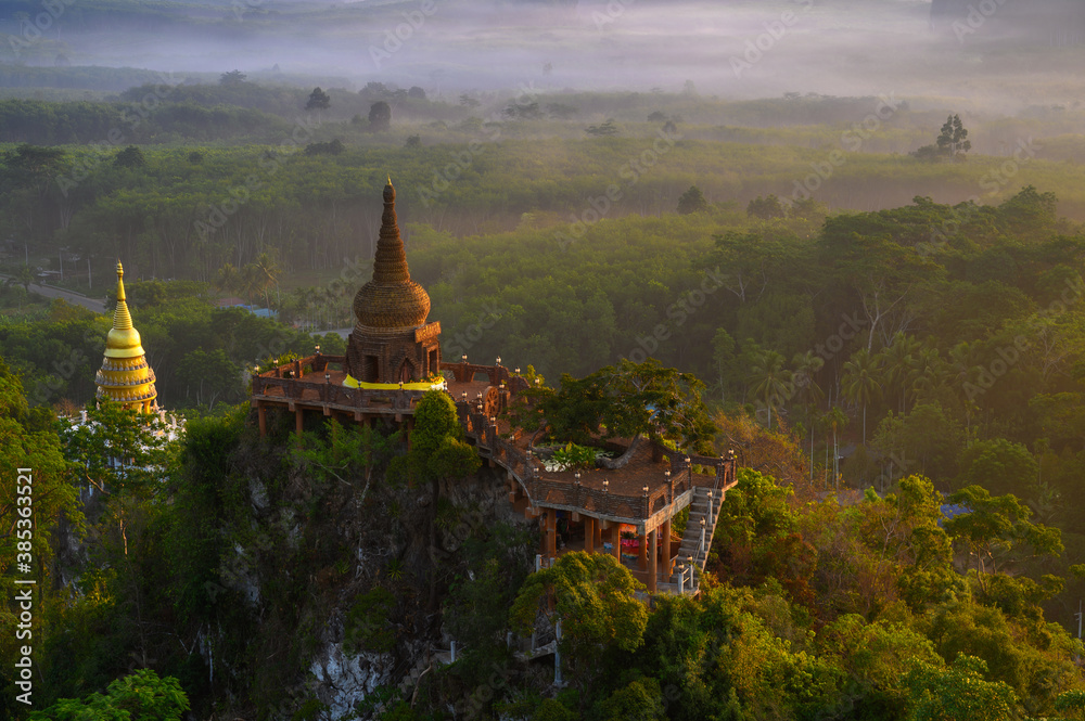 Naklejka premium View of Buddhism temple Thamma Park padoga on hill at sunrise in Ban Khao Na Nai village in Phanom, Surat Thani, Thailand