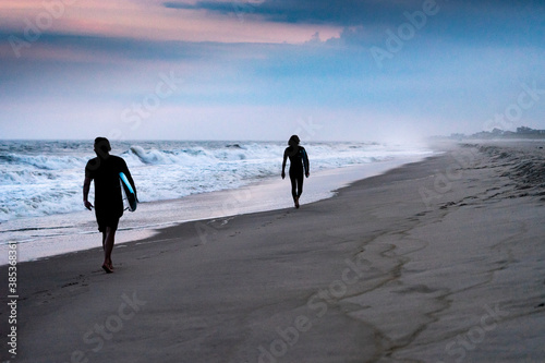 Photography Surfers walk on the beach at sunset after surfing in The Hamptons, New York