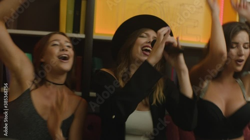 girls sing karaoke at nightclub in neon lights photo