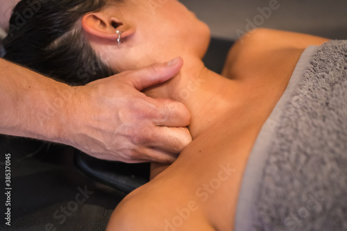 Detail of the neck massage to a young woman from a physiotherapist. Physio  osteopathy